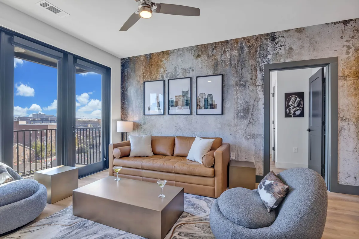 A relaxed interior space spotlighting a leather sofa, coffee table, and contemporary artwork. The area is set up for socializing or unwinding after a busy day in Nashville.