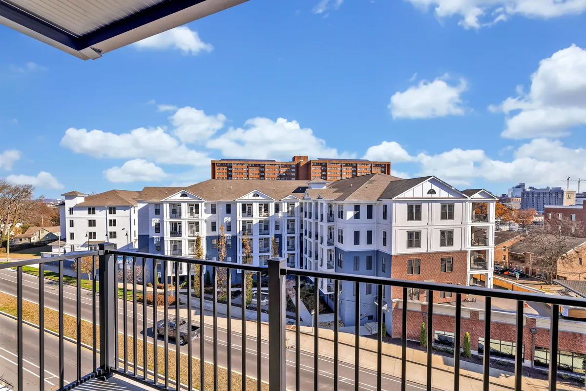 A relaxed view from a private balcony, featuring a balcony railing overlooking vibrant city buildings and an open sky, evoking tranquility and urban lifestyle.