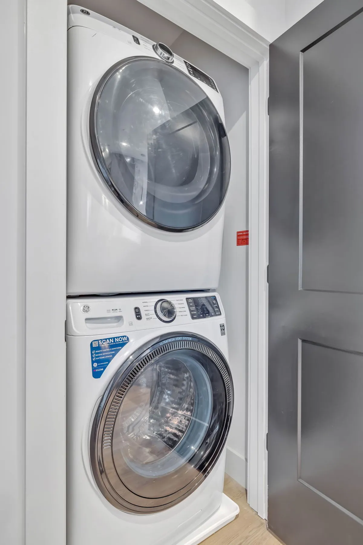 A dedicated laundry area featuring a stacked washer and dryer with modern design elements. The space looks clean, efficient, and seamlessly integrated into the unit.