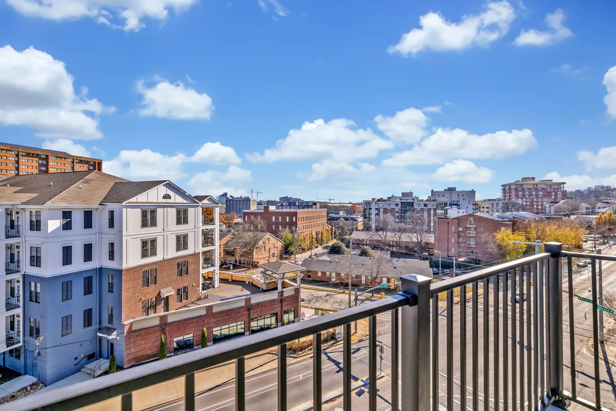 A sweeping urban skyline viewed from a balcony, with scattered clouds overhead. The vantage point suggests a sense of anticipation and possibility, perfect for gathering with friends to plan the night or savor the cityscape after an evening out.